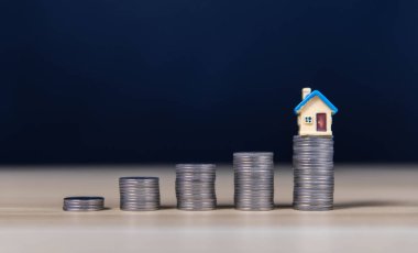 Yığınla para ve ev. Finansal konsept, kar amaçlı işletme yatırımlarını ilerideki büyüme ve başarı için en üst düzeye çıkarmak amacıyla banka hesabına yatırım yapmak. Bir ev almayı planlıyorum.