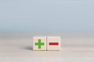 Ahşap blok artı ve eksi simgeleri gösterir, artıları ve eksileri karşılaştırma kavramı, negatifin karşısındadır. artı eksi 'ye karşı seçim yapmak, karar iyi ve kötüye karşı