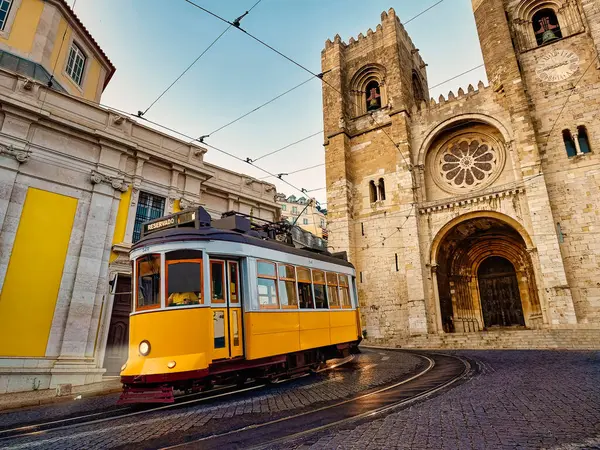 Lizbon, Portekiz 'deki Santa Maria katedralinin önünden geçen ünlü sarı bir tramvay. Alacakaranlıkta veya alacakaranlıkta.