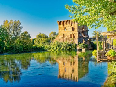 Borghetto Konsolosu Mincio. Visconti Köprüsü 'nün kalıntıları İtalya' nın Veneto bölgesinde Valleggio sul Mincio 'nun bir köyü olan Borghetto Konsolosu Mincio' nun sularına yansıyor.