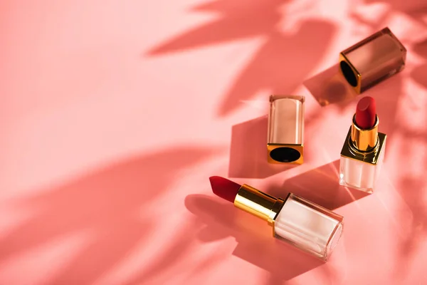Rode Lippenstift Beauty Product Een Roze Achtergrond Zonneschermen Van Bloemen Rechtenvrije Stockafbeeldingen