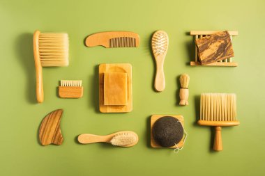 Yeşil arka planda cilt ve saç bakımı için sıfır atık banyo çevre dostu ve plastiksiz doğal ahşap aksesuarlar. Fırçalar ve taraklar, düz yatış