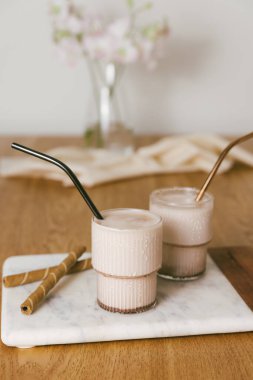 Buzlu çikolatalı milkshake mermer tepside dalgalı bardaklarda. Tahta masada kakao sütlü içecek. Dikey video