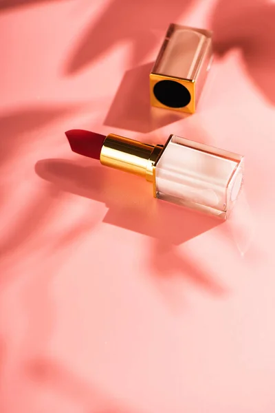 stock image Red lipstick beauty product on a pink background. Sun shadows from flowers, copy space