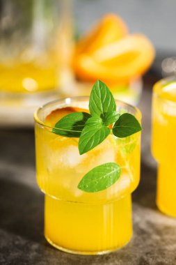 Limonata veya meyve ve fesleğenli mojito kokteyli. Limonlu ve portakallı soğuk yaz içeceği gri masada.