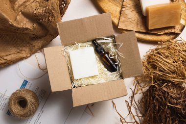 Paramparça beyaz kağıt üzerinde serum şişeleri olan bir güzellik kutusu. Çevre dostu karton hediye kutusu ve sıfır atık kozmetik ürünleri. Teslimat servisi deposunda çevrimiçi mağaza siparişleri.