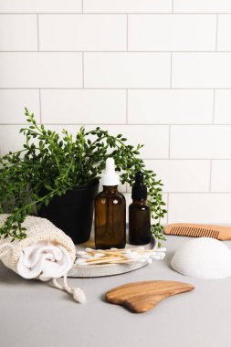 Sürdürülebilir sıfır atık yaşam tarzı serum şişeleri ve beyaz fayanslı banyo aksesuarları. Metnin için boşluk kopyala