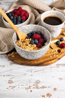 Bir kase ev yapımı yulaf gevreği yoğurt ve ahşap bir masada taze böğürtlen. Ceviz ve kuru üzümlü sağlıklı bir kahvaltı.