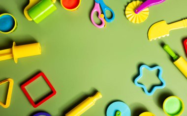 Yeşil arka planda çocuklar için hazırlanmış plasticin ya da kil hamur oyun araçları etkinliği. Okul ya da anaokulunda eğitim için kalıp, şekil ve oklava..