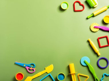 Yeşil arka planda çocuklar için hazırlanmış plasticin ya da kil hamur oyun araçları etkinliği. Okul ya da anaokulunda eğitim için kalıp, şekil ve oklava..