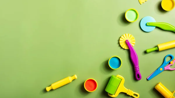 Plasticine or clay play dough tools activity set for children on a green background. Molding stack, shape, and rolling pin for education in school or kindergarten.