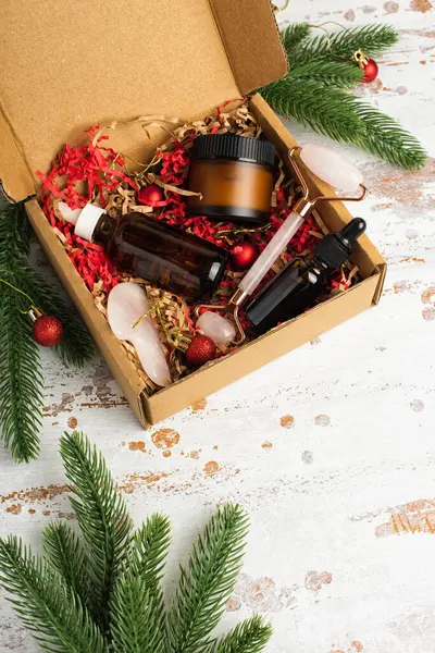 Christmas beauty box with skin care organic cosmetics products on red and brown shredded pink paper packing material. Delivery of fragile objects