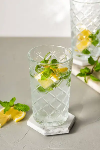 Stock image A refreshing summer drink or alcoholic cocktail with ice, mint and lemon on a sunny day. A fresh healthy cold lemonade drink. Sparkling water with lemon