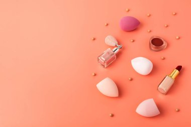 Different decorative cosmetics on pink background. Colorful beauty sponges or blenders, lipstick, blushes. Makeup tools for applying makeup. Horizontal shot. Copy space for text. clipart