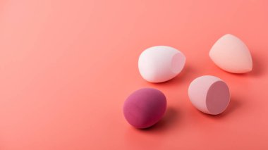 Renkli güzellik süngerleri ya da pembe arka plandaki kutuda mikserler. Vakıf ve kapatıcı için makyaj aletleri. Dikey çekim. Metin için alanı kopyala.