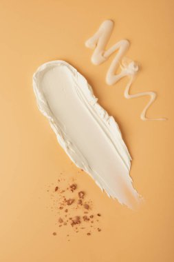 Bej bir arka planda kremsi doku örnekleri ya da lekeleri. Cilt bakım kremi, yüz serumu, vücut losyonu.