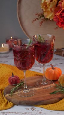Kırsal bir tatil masasında sonbahar baharatlı kokteyl ve şarap. Cadılar Bayramı için ev yapımı Sangria, tarçınlı Şükran Günü ve biberiyeli Sangria. Dekoratif tekstil balkabakları ve mumlar