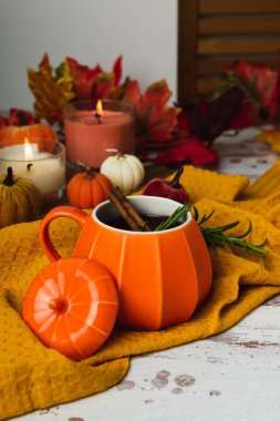 Sonbahar balkabağı kabağı şarabı tarçınlı, kır masasında. Geleneksel sonbahar baharatlı içeceği turuncu seramik kupalarda. Dekoratif tekstil balkabakları ve mumlar