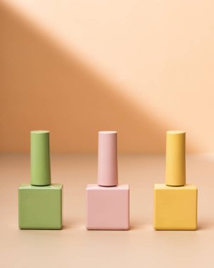 Kadın manikürü için yeşil, tereyağı sarısı ve pembe vernik şişeleri güzellik salonu cazibesi, jel tırnak tasarımı. Cazip güzellik salonu için arka plan