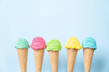 Külahta renkli dondurma kepçeleri, parlak mavi arka plan. Üst görünüm