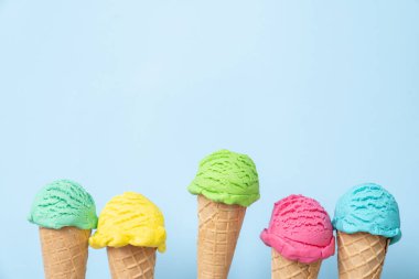 Külahta renkli dondurma kepçeleri, parlak mavi arka plan. Üst görünüm