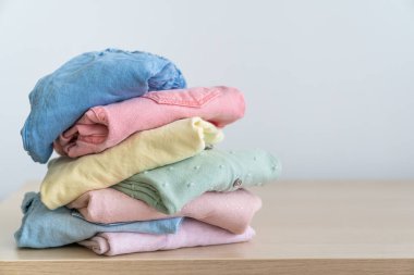 Temiz, yeni yıkanmış kadın kıyafetleri yığını ahşap masanın üzerinde. Masada bir yığın gömlek ve kazak var.