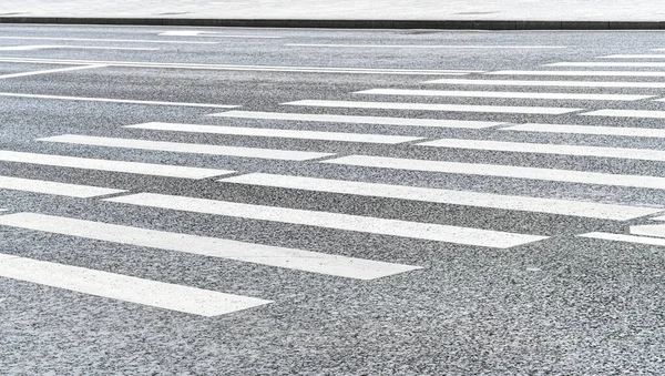 Crosswalk on the road background. Pedestrian crossing on an asphalt road. Crosswalk on the street for safety.