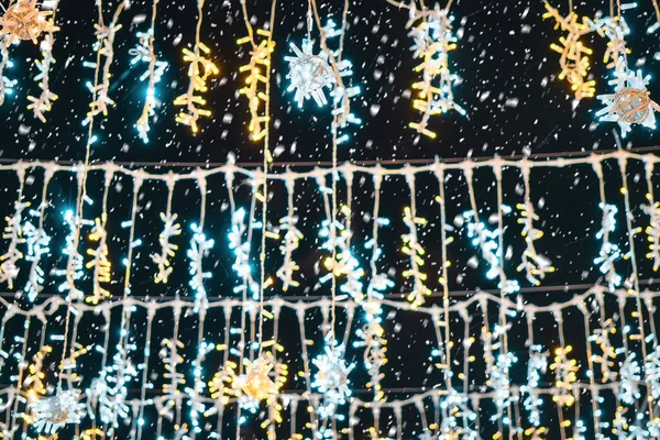 Christmas garlands with LED lamps with falling snow at night. Xmas decorations.