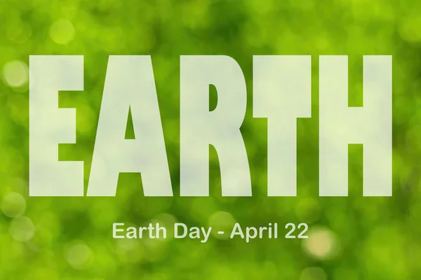 Lettering Earth Day April 22 on the green bokeh background. Earth day concept, protection of the planet from pollution, improvement of environmental ecology and nature conservation.