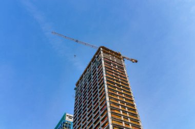 A crane building a modern skyscraper against a blue sky. Construction site.