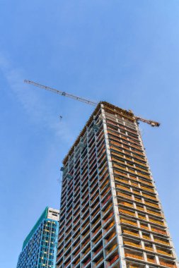 A crane building a modern skyscraper against a blue sky. Construction site.