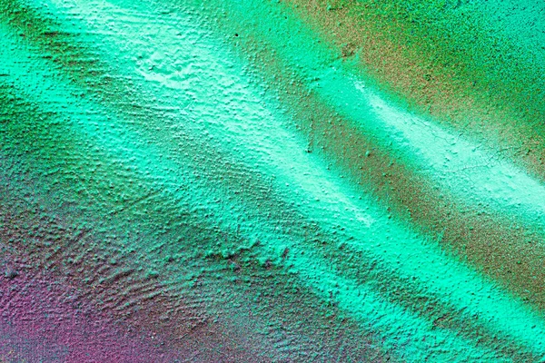 A fragment of colorful graffiti painted on a wall. Abstract urban background for design. Spray painting art.