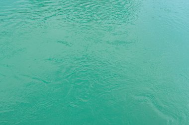 The texture of the waves of turquoise color of fast-flowing water in the river. Abstract nature background.