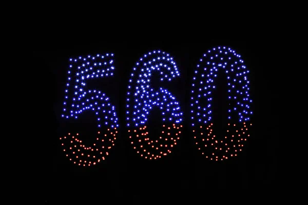 在漆黑的夜空背景上显示出五彩斑斓的无人驾驶灯光 一个用发光的无人驾驶飞机做成的数字 五百六十个 560个 — 图库照片