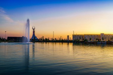 UZBEKISTAN, TASHKENT - 25 Nisan 2023: Yeni Özbekistan parkının, bahar aylarında alacakaranlıkta Humo kuşu, göleti ve fıskiyesi ile birlikte çalgı şeklinde Bağımsızlık Anıtı 'nın bulunduğu bölgesi.