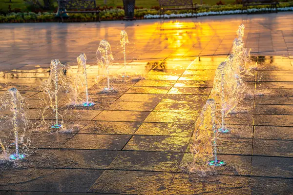 歩道には小さな噴水があり 日没や夏の公園の日の出に照らされています — ストック写真