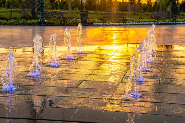人行道上的小喷泉 夏天的日落或日出时被阳光照亮 — 图库照片
