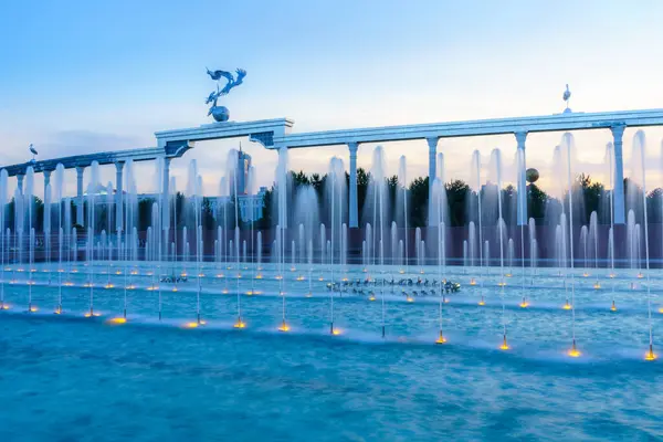 stock image Memorial and rows of fountains illuminated by sunlight at sunset or sunrise in the Independence Square at summertime, Tashkent, Uzbekistan.