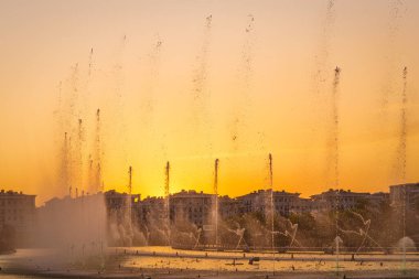 Suni gölün üzerindeki büyük fıskiyeler yaz akşamı Taşkent şehir parkında güneş ışığıyla aydınlanıyor..