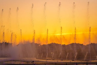 Suni gölün üzerindeki büyük fıskiyeler yaz akşamı Taşkent şehir parkında güneş ışığıyla aydınlanıyor..