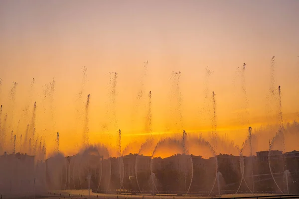 夏の夜にタシュケント市公園の日没時の日光に照らされた人工池の大きな噴水 — ストック写真