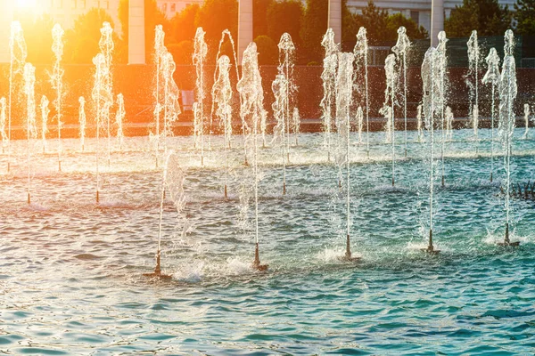 夏日日落或日出时 一排排的喷泉被阳光照射在公园里 — 图库照片