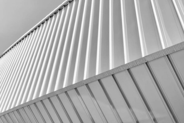 Black and white fragment of a modern building covered with metal aluminum panels.