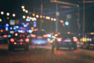 Yürüyen arabaların ve fenerlerin bulanık ışıkları yağmurda şehrin ıslak asfaltına yansıyor. Klasik film estetiği. Yağmurlu kötü hava konsepti.
