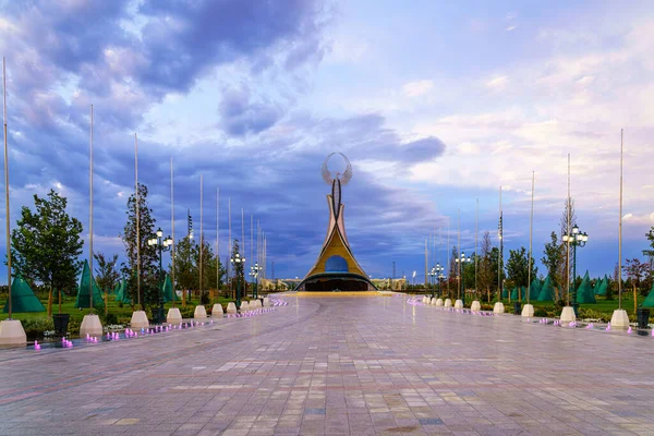 UZBEKISTAN, TASHKENT - 15 AĞUSTOS 2023: Yazın Yeni Özbekistan parkında alacakaranlıkta bir Humo kuşuyla birlikte bir çelik heykel şeklinde Bağımsızlık Anıtı.