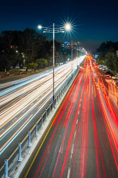 Stock image Traces of headlights of moving cars on the highway and street lights in the city at night. Blurred car movement.