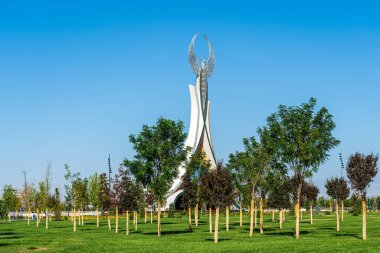 UZBEKISTAN, TASHKENT - 15 EYLÜL 2023: Yaz mevsiminde Yeni Özbekistan parkında gündüz vakti bir Humo kuşu ile birlikte bir çelik şeklinde Bağımsızlık Anıtı.