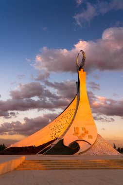 Özbekistan, Taşkent - 4 Ekim 2023: Yeni Özbekistan parkında dramatik kliodi gökyüzü ile alacakaranlıkta bir Humo kuşuyla birlikte bir çelik heykel şeklinde Bağımsızlık Anıtı.