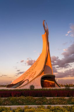 Özbekistan, Taşkent - 4 Ekim 2023: Yeni Özbekistan parkında dramatik kliodi gökyüzü ile alacakaranlıkta bir Humo kuşuyla birlikte bir çelik heykel şeklinde Bağımsızlık Anıtı.