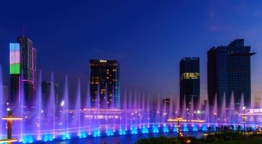 Özbekistan, Taşkent - 29 Eylül 2023: Taşkent City Parkı 'nda gece vakti lazer aydınlatma ve hafif müzikli bir çeşme.